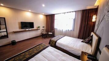 Une chambre d’hôtel avec deux lits, une télévision, un bureau et une chaise.