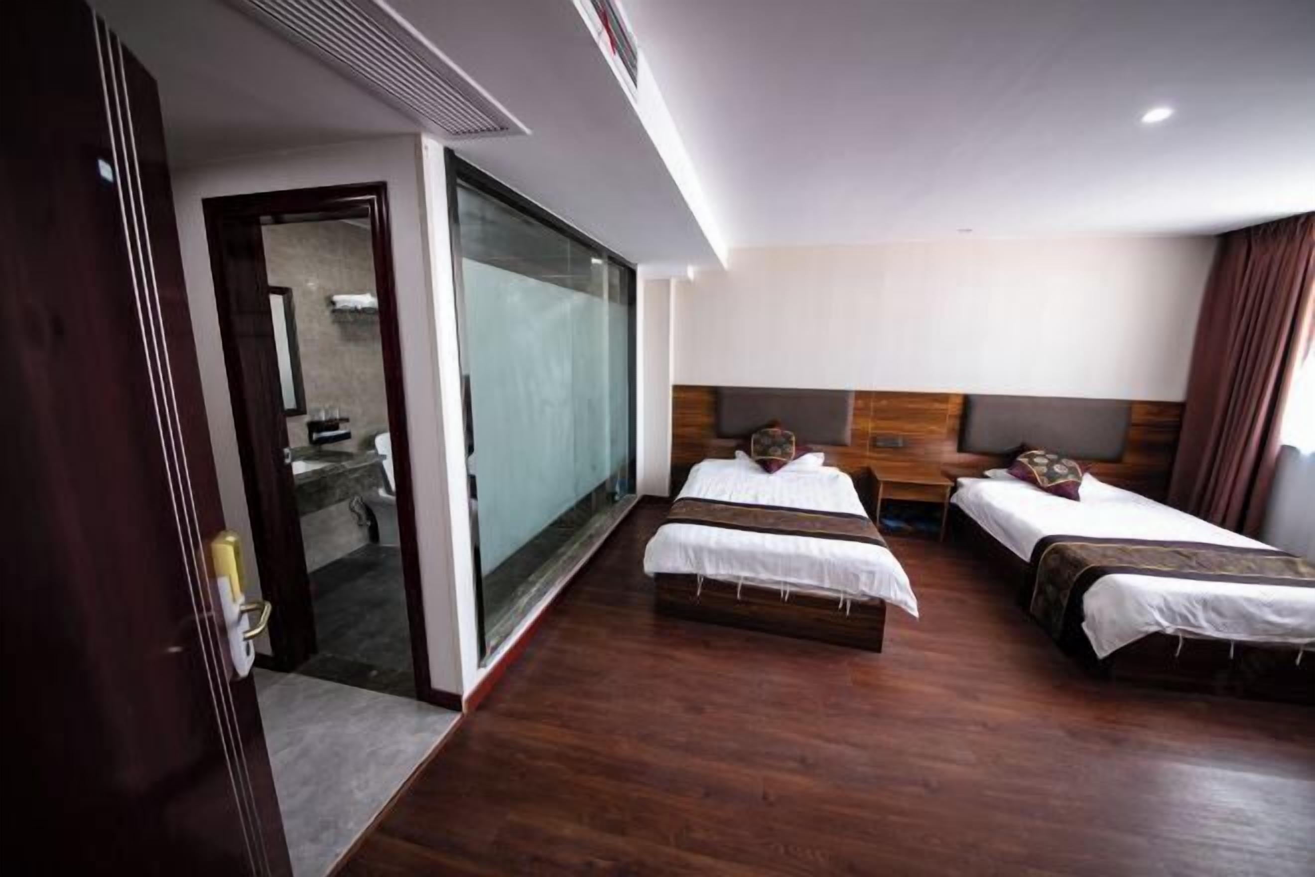 A hotel room with two beds, a large sliding glass door, and a wooden floor.