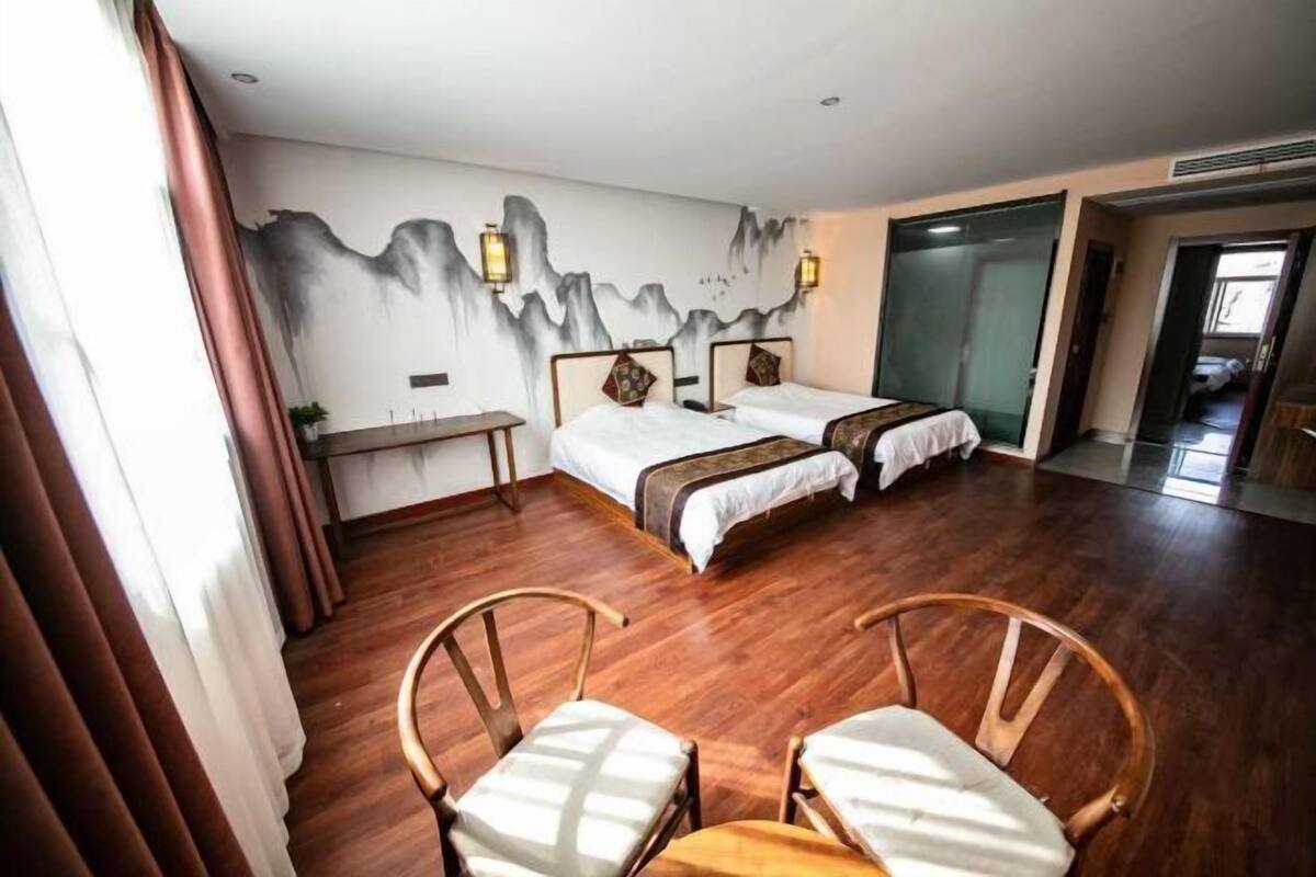 Une chambre d’hôtel avec deux lits, un plancher en bois, un bureau et une chaise.