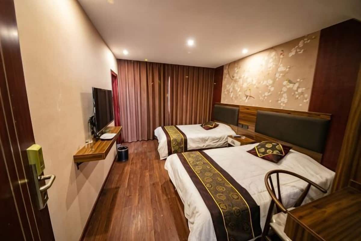 Une chambre d’hôtel avec deux lits, une télévision, un bureau et une chaise.