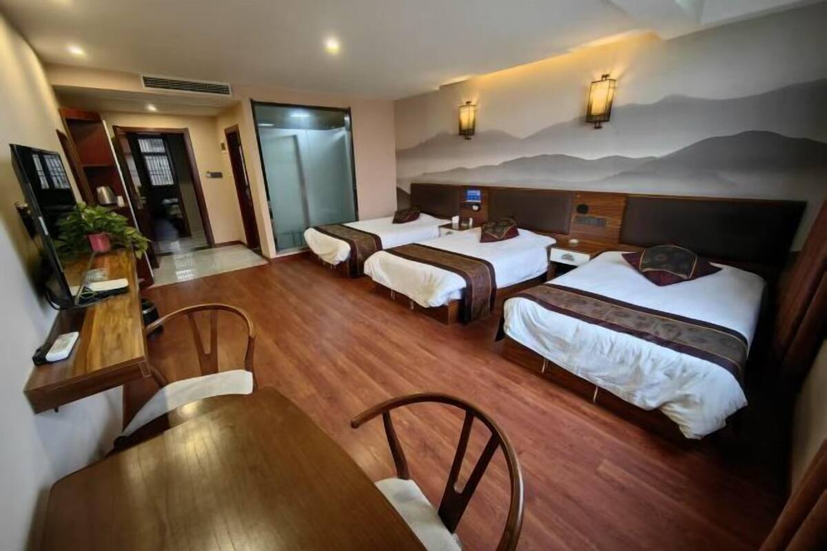 Une chambre d’hôtel avec deux lits, une table à manger en bois et une chaise.