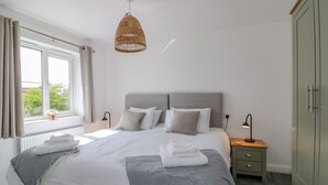 Quarto bem arrumado com uma cama grande, mesas de cabeceira, guarda-roupa e luminária pendente.