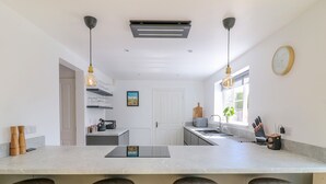 Cozinha moderna com ilha central, banquetas, iluminação pendente e uma janela ampla.