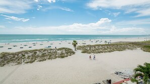 A beach with a clear sky, sandy shore, and a few people walking. - Treasure Island Oceanfront Studio with Balcony & Heated Pool (Treasure Island)