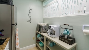 A kitchen with a refrigerator, microwave, toaster, coffee maker, and a coffee station. - Treasure Island Oceanfront Studio with Balcony & Heated Pool (Treasure Island)