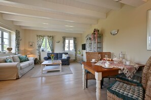 Ein geräumiges Wohnzimmer mit einer Couch, einem Couchtisch und einem Esstisch, gedeckt für eine Mahlzeit.