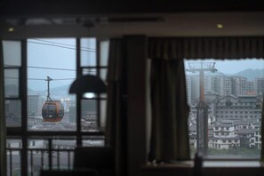 A room with a large window, a lamp, and a view of a cable car. - JIAN GE SHI GUANG TRAVEL HOTEL(Zhangjiajie Tianmenshan Cableway Station) (Zhangjiajie)