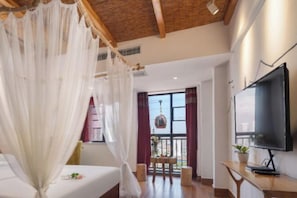 Una habitación con cama, televisión, balcón con hamaca y vista a la ciudad.