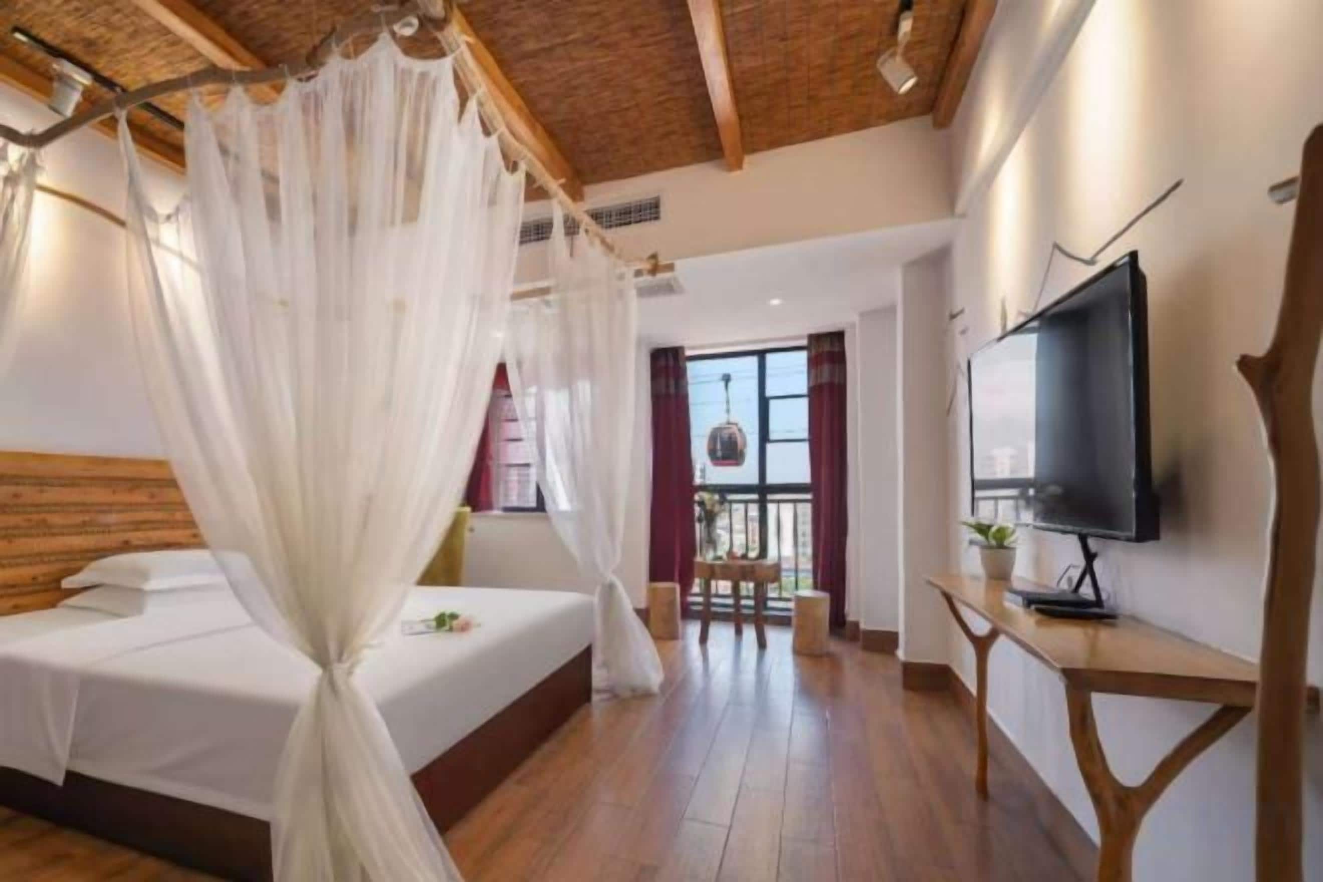 A bedroom with a bed, a TV, and a window.