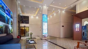 A modern lobby with a reception desk, seating area, and a digital information board.