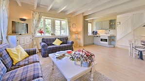 A cozy living room with a plaid sofa, a coffee table with magazines, and a window with curtains. - Landhaus Vilmnitz - Wohnung 9 - Landhaus Vilmnitz, Wohnung 9 (Putbus)