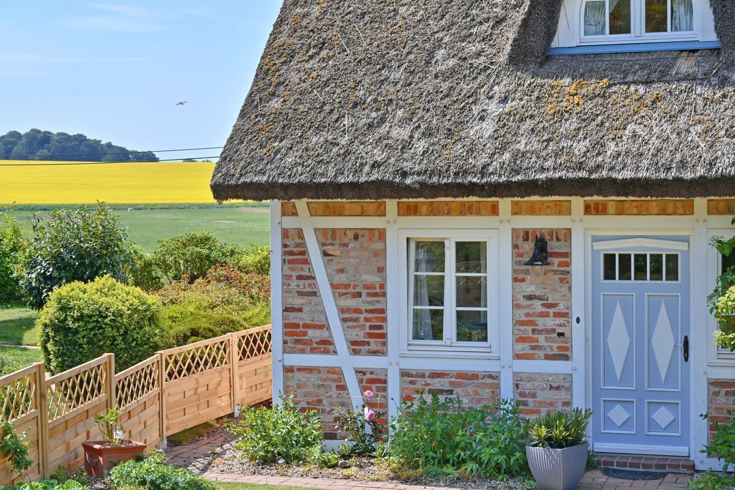 Un affascinante cottage con tetto di paglia, facciata in mattoni e una porta bianca.
