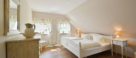 Une chambre à coucher avec un grand lit, deux tables de chevet, une commode et un miroir.