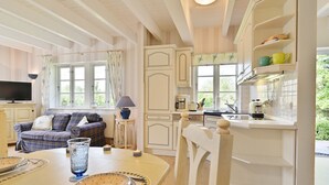 Een gezellige woonkamer met een bank, een eettafel met borden en glazen, en een keuken met een spoelbak en kastjes.