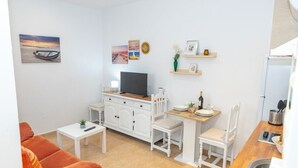 Un espacio habitable compacto con kitchenette, comedor y zona de estar.