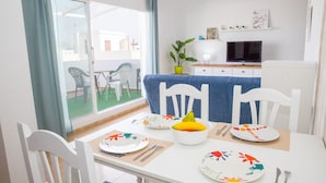 A dining area with a table set for four, chairs, a television, and a view of the outside.