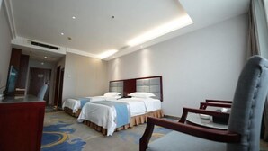 A hotel room with two beds, a desk, a chair, and a television.