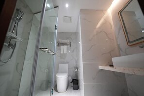 A modern bathroom with a glass shower enclosure, a white toilet, and a marble-tiled wall.