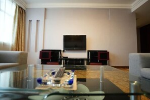 A hotel room with a glass coffee table, two armchairs, a flat-screen TV, and a pair of speakers. - Quanjun Hotel (Dawu)