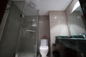 A modern bathroom with a glass shower enclosure, a white toilet, and a marble countertop.
