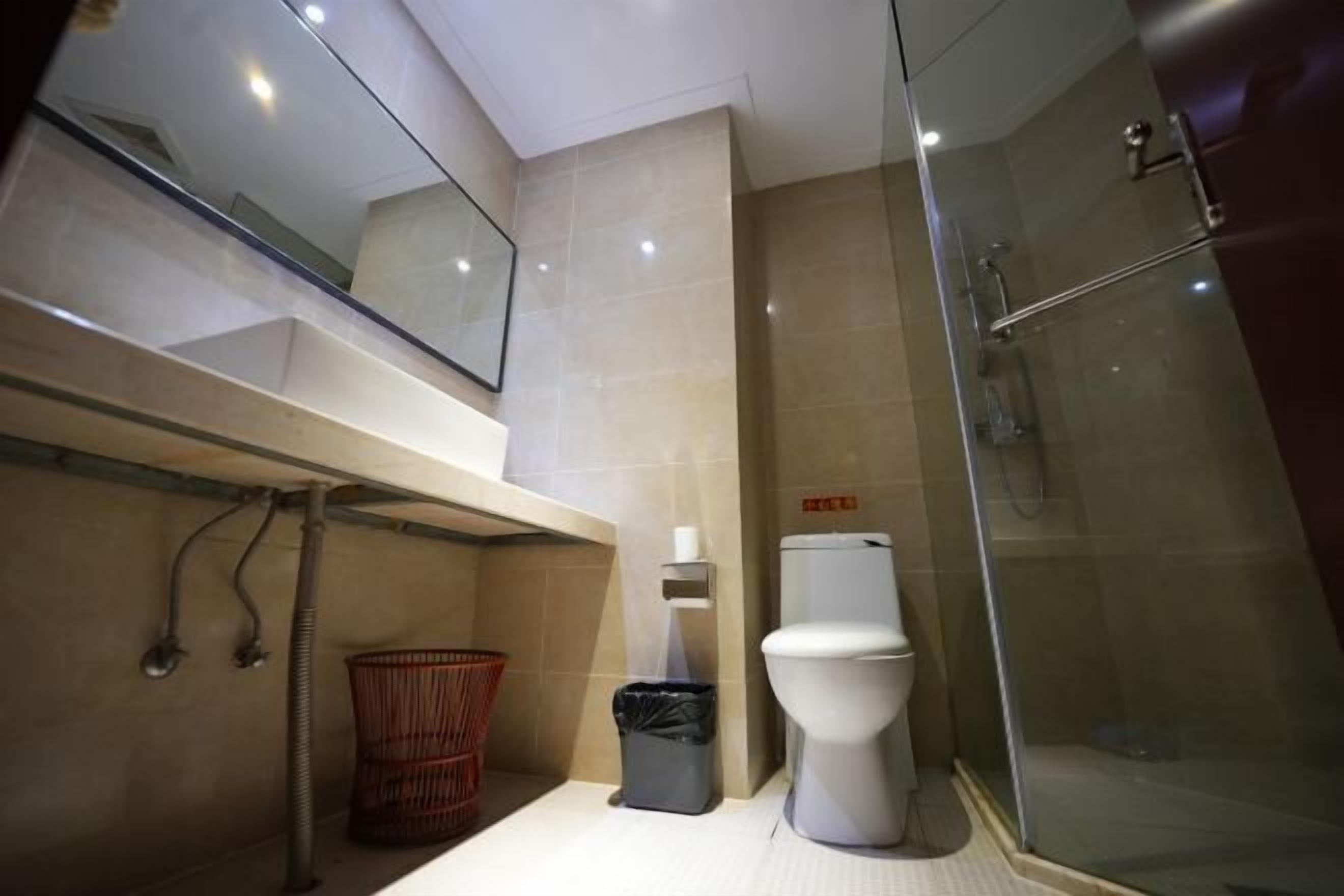 A modern bathroom with a toilet, shower, and a glass-enclosed shower area.