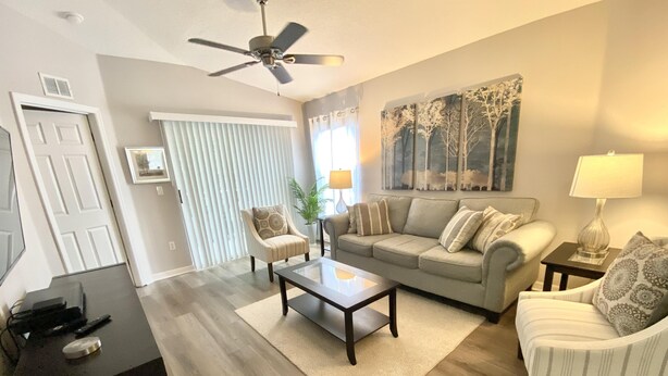 A living room with a sofa, armchairs, a coffee table, a ceiling fan, and a painting on the wall. - Grand Palm Community, Picnic Benches, Tennis Court and Much More!! (Kissimmee)