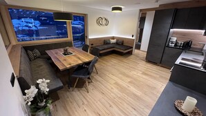 A modern interior with a wooden dining table, seating area, and a kitchen with a coffee machine. - Lovely apartment for 4 guests with WIFI, TV and panoramic view (Stumm)
