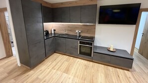 A modern kitchen with dark cabinetry, a wooden countertop, and a built-in oven. - Lovely apartment for 4 guests with WIFI, TV and panoramic view (Stumm)