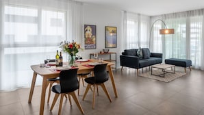 A modern living room with a dining area, featuring a sofa, a coffee table, and a dining table set with chairs.
