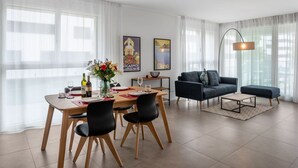 A modern living room with a dining area, featuring a sofa, a coffee table, and a dining table set with chairs.