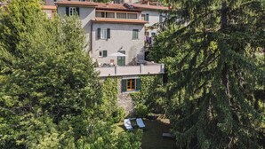 Uma villa numa encosta com um jardim em terraços, área de estar ao ar livre e vista para a floresta circundante.