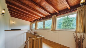 Escada de madeira que leva a um quarto no mezanino com vista para uma floresta.