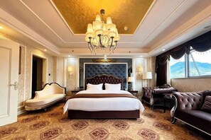 A hotel room with a large bed, a chandelier, a sofa, and a view of the mountains. - Xundian Fengyi Hotel (Tangdian Passenger Transport Terminal) (Xundian)