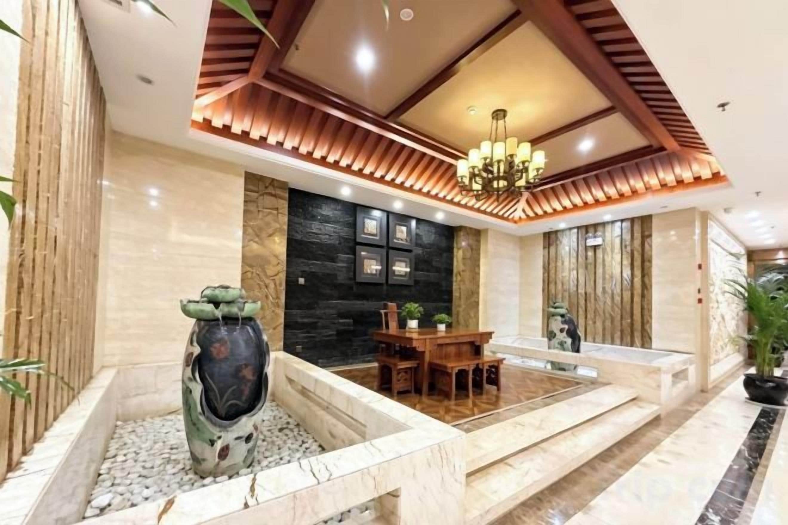 Un vestíbulo con mostrador de recepción, zona de comedor, un jarrón decorativo y una araña.