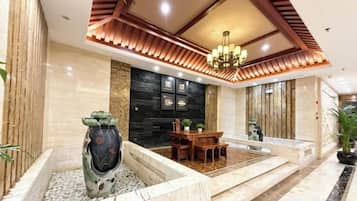 Un vestíbulo con mostrador de recepción, zona de comedor, un jarrón decorativo y una araña.