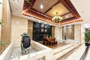 Eine Lobby mit einer Rezeption, einem Essbereich, einer dekorativen Vase und einer Chandelier.