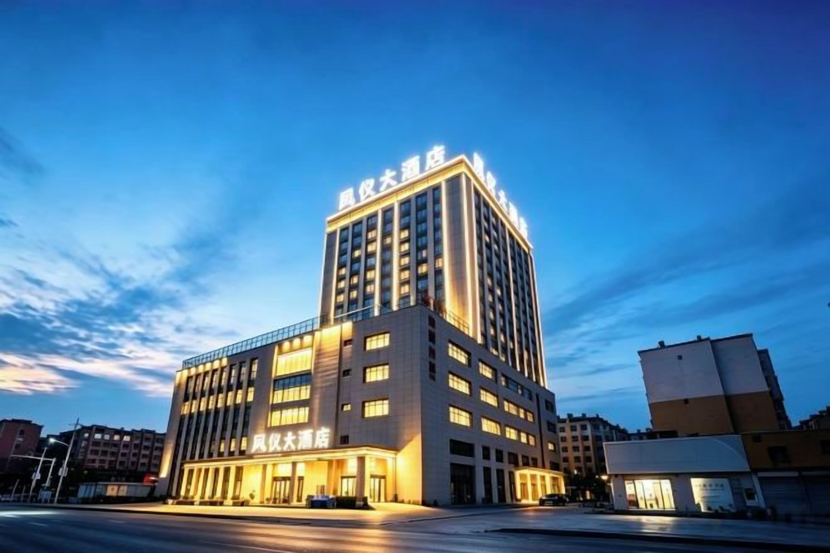 Un hotel de varios pisos con una entrada destacada y señalización, situado en un entorno urbano.