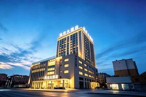 A multi-story hotel with a prominent entrance and signage, located in an urban setting. - Xundian Fengyi Hotel (Tangdian Passenger Transport Terminal) (Xundian)