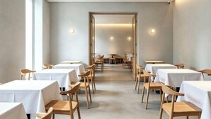 Un restaurant amb diverses taules i caires, una paleta de colors neutres i un disseny interior modern.