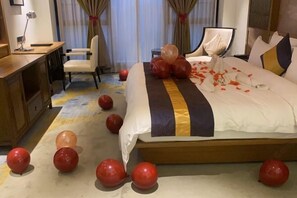 A hotel room with a bed, a desk, a chair, and balloons scattered on the floor. - Qianshan Heyue Hotel (Suiyang)