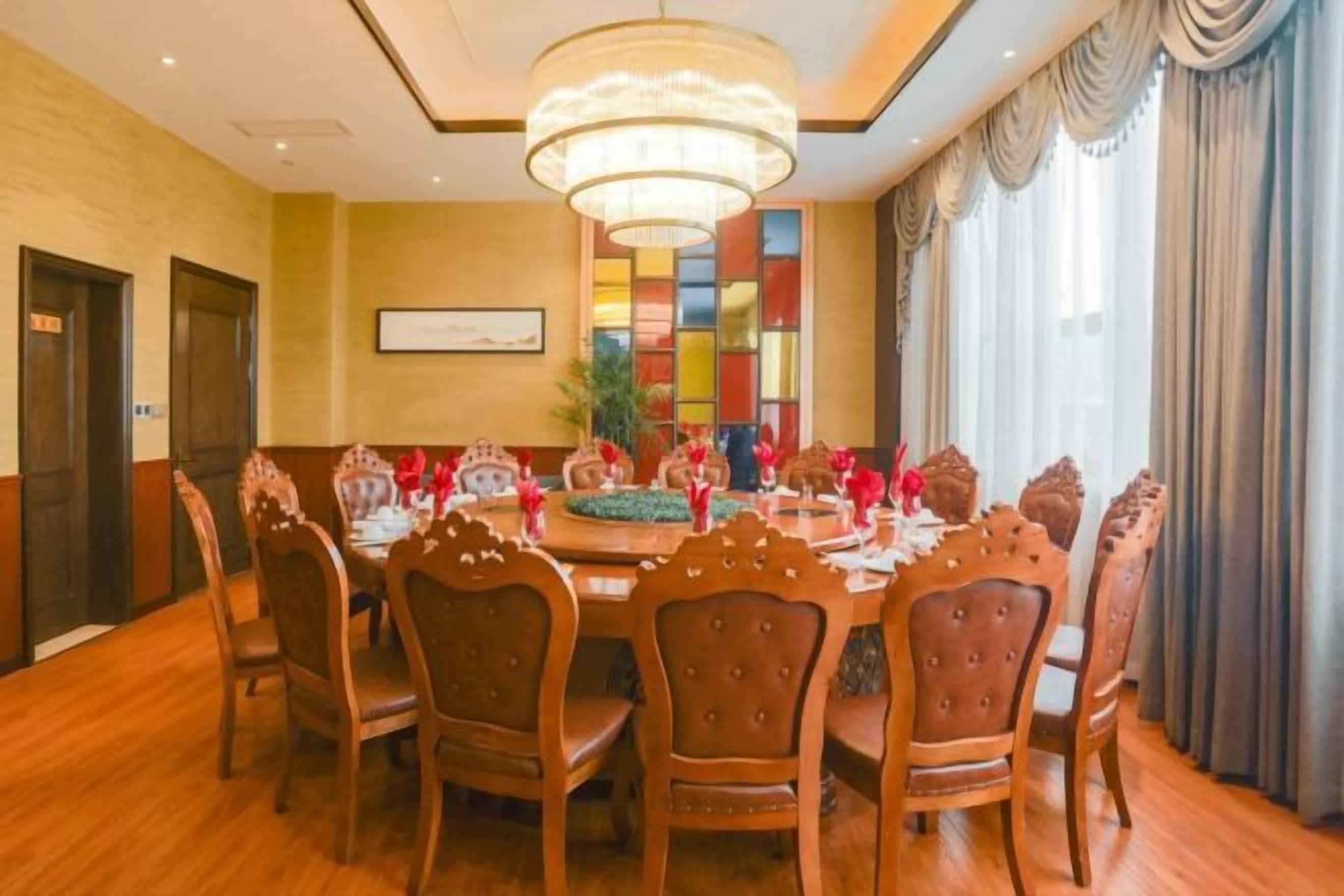 A conference room with a round table, wooden chairs, and a chandelier.
