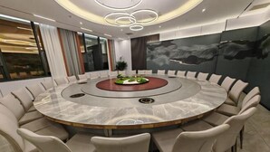 A modern conference room with a circular table, beige chairs, and a central decorative piece. - Qianshan Heyue Hotel (Suiyang)