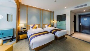 A hotel room with two beds, a desk, a chair, a nightstand, and a door. - Qianshan Heyue Hotel (Suiyang)