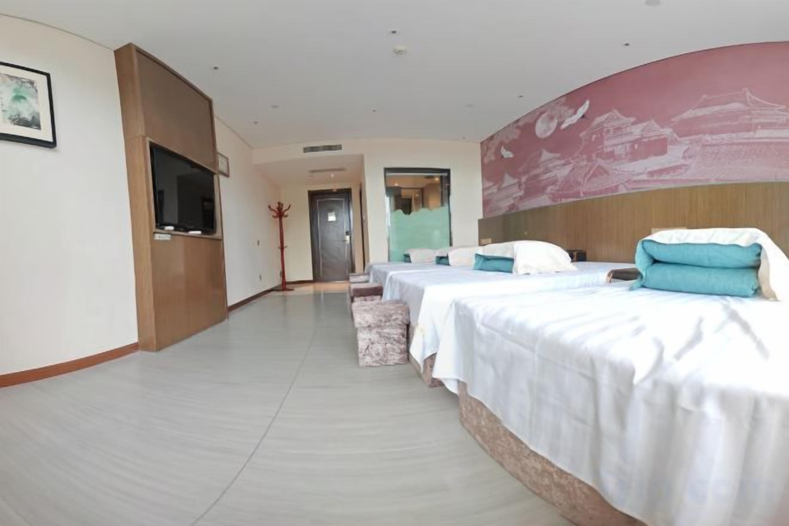 A hotel room with three beds, a TV, and a large painting on the wall.