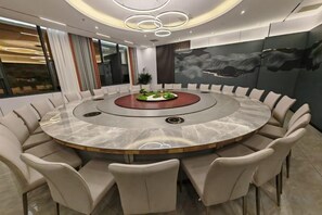 A modern conference room with a circular table, beige chairs, and a central plant. - Qianshan Heyue Hotel (Suiyang)