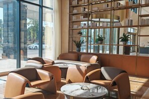 A modern lounge area with leather seating, a marble coffee table, and a large bookshelf filled with books and decorative items. - Qianshan Heyue Hotel (Suiyang)