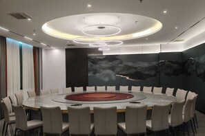 A conference room with a round table, chairs, and a modern ceiling design. - Qianshan Heyue Hotel (Suiyang)