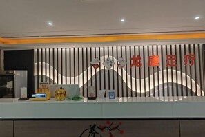 A reception desk with a modern design, featuring a logo and a nameplate. - Qianshan Heyue Hotel (Suiyang)