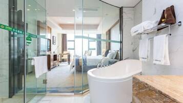 Un baño moderno con una bañera grande, un box de ducha de vidrio y una pared de mármol.