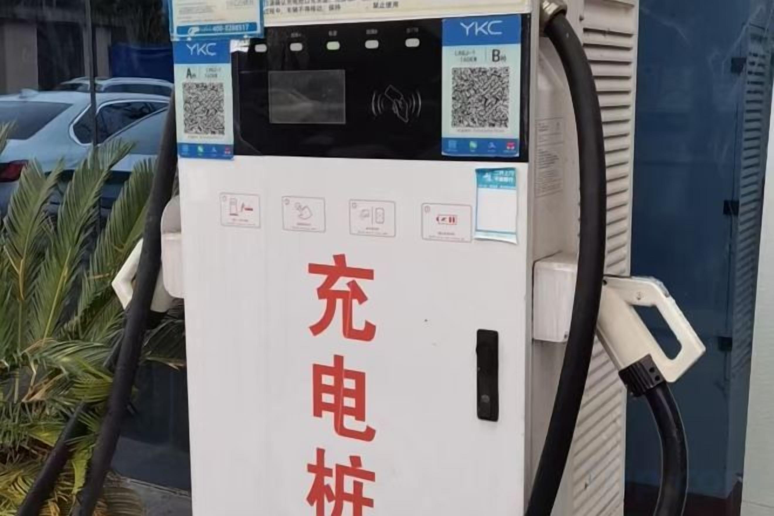 A public electric vehicle charging station with QR codes and instructions.